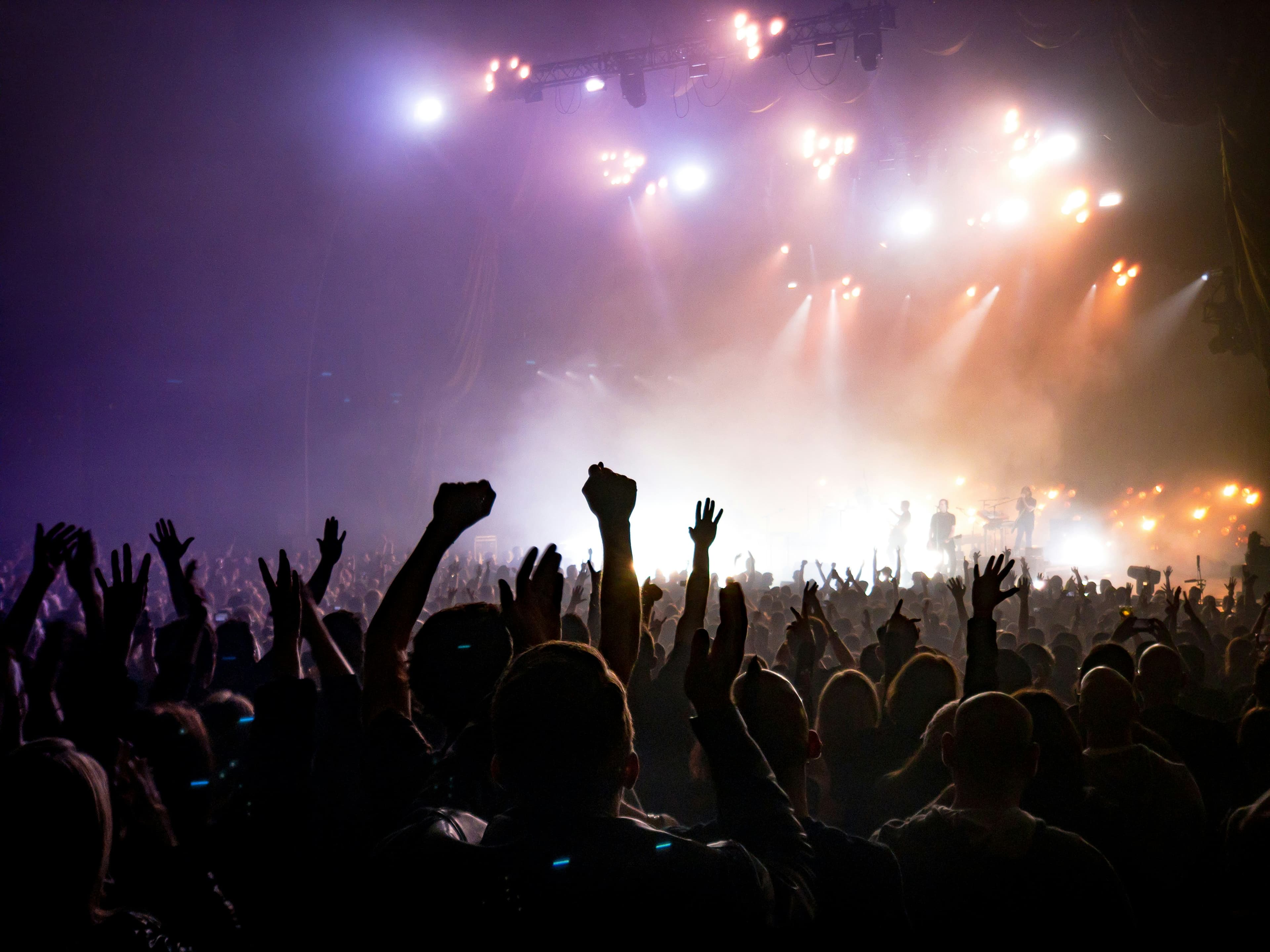 Crowd dancing under bright teal stage lights